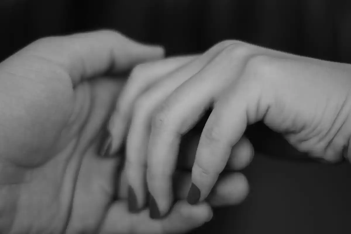 A monochrome photograph showcasing two hands intertwined, representing affection and solidarity.