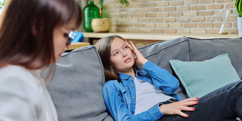 Sad Young Woman In Meeting With Psychologist Sitting On Sofa
