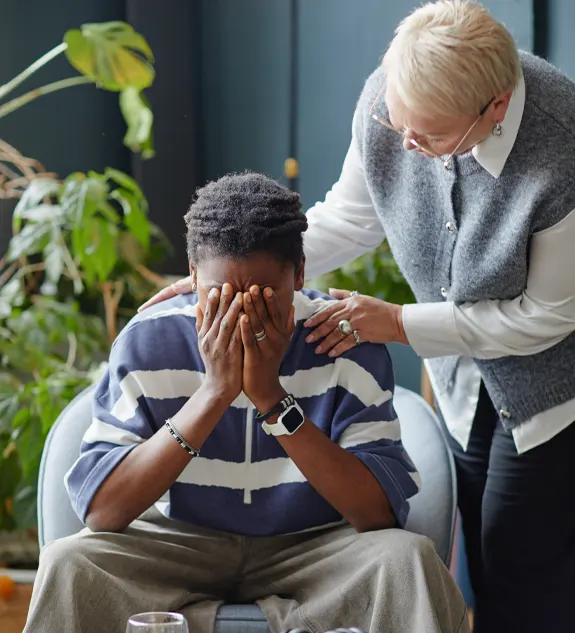 Middle Aged Woman Comforting Young Adult Man Crying